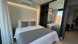 a hotel room with two beds and a mirror at Porto Alto Resort in Porto De Galinhas