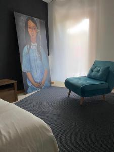 a room with a blue chair and a painting at Mountain House in San Giovanni Bianco