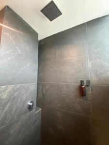 La salle de bains est pourvue d'une douche et d'un mur en carrelage. dans l'établissement Nayfer Suites, à Playa del Carmen