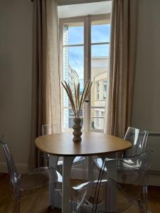 a table with a vase on it in front of a window at Le petit Rameau - T2 hypercentre in Clermont-Ferrand