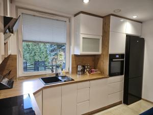 a kitchen with white cabinets and a large window at Domek Zacisze Myśli in Elblag +10 photos