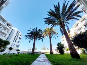 three palm trees in front of a building at Apartamento céntrico con playa y piscina in Playa del Ingles