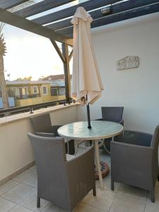 a table with an umbrella on a balcony with chairs at Lovely 2 Bed Apartment Aphrodite Gardens, Paphos, Cyprus in Nea Paphos