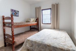 a bedroom with two bunk beds and a window at Casa azul, 2 quadras praia-wifi-garagem -churrasqueira e fogão a lenha - Aceita Caes -Caiçara-Praia Grande in Praia Grande