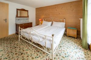 a bedroom with a white bed with a wooden wall at Ferienapartments Chalet Solvay in Zermatt