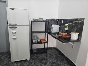 a kitchen with a white refrigerator and a black shelf at CIG Hostel in Goiânia