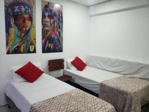 two beds in a room with paintings on the wall at Apartamento no centro de São Paulo in Sao Paulo