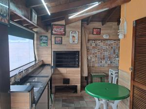 Una cocina con fregadero y una mesa verde. en Casa dos Prados, en Peruíbe