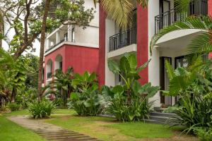 a red and white building with trees and plants at Scenic 1BHK Apartment by tisyastays in Candolim