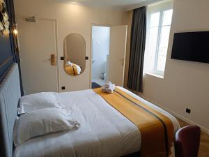 ein Schlafzimmer mit einem großen Bett und einem Spiegel in der Unterkunft The Originals Boutique, Hôtel Angleterre, Fécamp in Fécamp + 9 Fotos