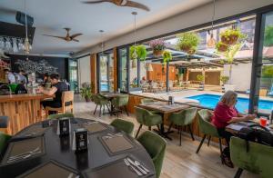 Un restaurante con piscina y gente sentada en mesas. en KC Hotel San Jose, en San José