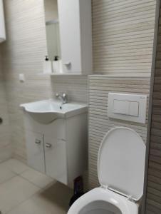 a bathroom with a white toilet and a sink at Twins Apartment in Strumica +15 photos