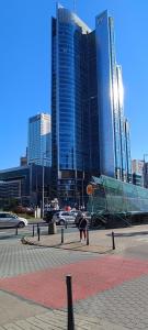 een persoon die voorovergebogen staat voor een paar hoge gebouwen bij Top Apartamenty Centrum - Metro Rondo ONZ in Warschau