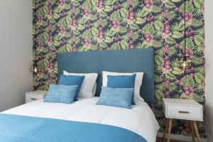 een bed met blauwe en witte kussens en een bloemenbehang bij Sta Catarina - 2 Bedroom Apartament in Porto