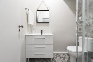 een witte badkamer met een toilet en een spiegel bij Sta Catarina - 2 Bedroom Apartament in Porto +15 foto's