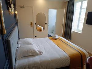 ein großes Bett in einem Zimmer mit einem Spiegel in der Unterkunft The Originals Boutique, Hôtel Angleterre, Fécamp in Fécamp