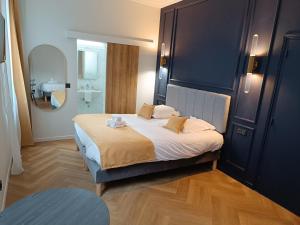 ein Schlafzimmer mit einem großen Bett und ein Badezimmer in der Unterkunft The Originals Boutique, Hôtel Angleterre, Fécamp in Fécamp