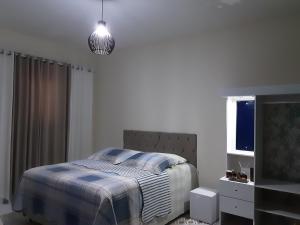 a bedroom with a bed and a pendant light at Casa de Praia Massaguaçu! Ao meio Áreas Arborizadas in Caraguatatuba +79 photos