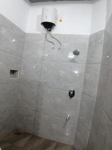 La salle de bains est pourvue d'une douche avec un mur blanc. dans l'établissement Luna Park & Resort, à Kottakupam