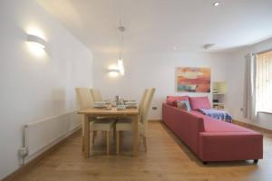 a living room with a table and a red couch at No3 By The Sea a 5 Star Cozy Coastal Cottage in Saint Monance +35 photos