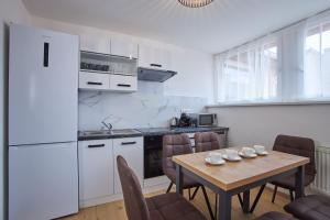 a kitchen with a wooden table with chairs and a table and a kitchen with white at Wenceslas Square Residence in Prague