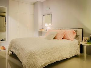 a white bedroom with a bed with pink pillows at Cozy 1br walk to BTS and Airport Rail Link Close to Malls 11 in Bangkok