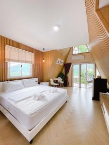 a large white bed in a bedroom with wooden walls at บ้านผูกรัก ทะเลหมอก ณ เขาค้อ in Khao Kho