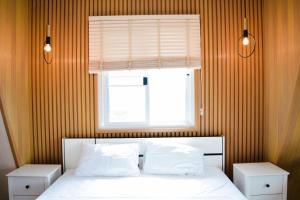 a bedroom with a bed with a window and white pillows at บ้านผูกรัก ทะเลหมอก ณ เขาค้อ in Khao Kho