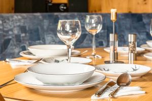 a wooden table with white dishes and wine glasses at Panorama Chalet mit Sauna Höllmaishof in Bischofshofen