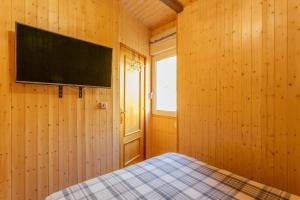 a bedroom with wooden walls and a flat screen tv at Sierra Nevada apartamento de madera muy cálido con buenas vistas y WiFi in Sierra Nevada