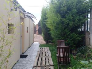 a wooden bench in a garden next to a building at Charmant Studio indépendant in Louvres