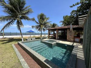 a swimming pool in front of a house with the beach at Morada da Praia - Porto de Pedras à Beira-Mar in Pôrto de Pedras