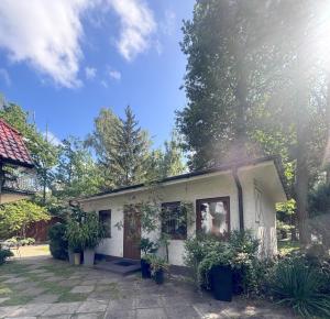 a small white house with plants in a yard at ahoj PRZYLESIE in Pobierowo
