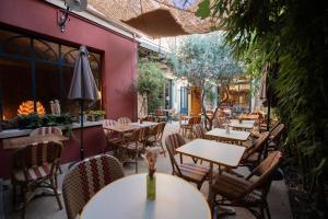 un restaurant en plein air avec des tables, des chaises et un parasol dans l'établissement La Maison Clémenceau, à Salon-de-Provence