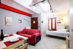 a living room with a red chair and a bed at Casa vacanze Re Cit Diano d'Alba in Diano dʼAlba
