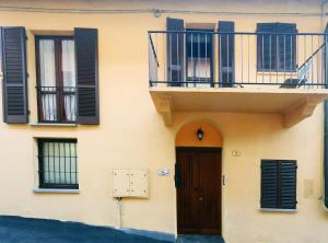 a building with black shuttered windows and a door at Casa vacanze Re Cit Diano d'Alba in Diano dʼAlba