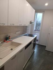 a kitchen with white cabinets and a sink and a window at Apartmán Meteorit 1 in Bratislava