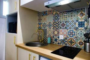 Una cocina con fregadero y una pared de azulejos. en Studio Centre-Ville Saint Gilles Les Bains, en Saint-Gilles-les-Bains 9 fotos más