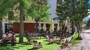 eine Gruppe von Stühlen und Tischen vor einem Gebäude in der Unterkunft Apartmány hotela CROCUS Štrbské Pleso in Štrbské Pleso