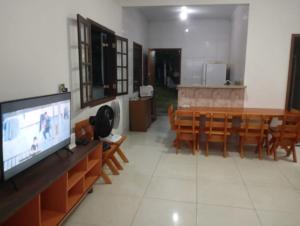 a living room with a television and a table and chairs at Casa Mar e Montanha 1, Vista para o Mar in Trindade