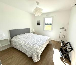 a white bedroom with a bed and a window at Les Gites des jardins d'Oscar l'Appartement in La Faye