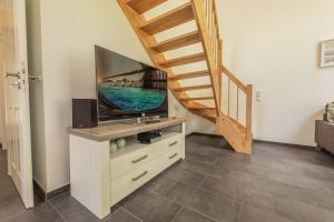 a living room with a television and a staircase at Lee - Nordhorn in Nordhorn