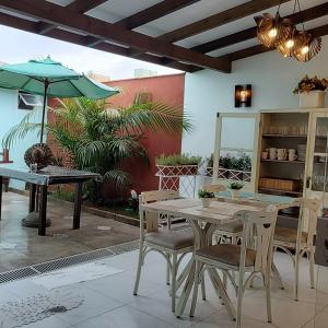 un patio avec une table, des chaises et un parasol dans l'établissement Pérola de Bombinhas, à Bombinhas 53 autres photos