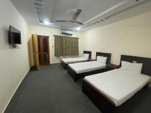 Una habitación de hotel con tres camas y un televisor. en Dream Inn 2, en Islamabad