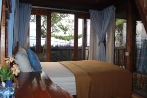 a bedroom with a bed and a table and windows at Boga Segara Villa And Resto in Nusa Penida