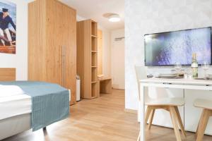 a bedroom with a bed and a desk with a tv at NINO-Boardinghouse 6 in Nordhorn