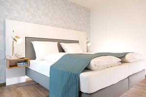 a bedroom with a large white bed with a blue blanket at NINO-Boardinghouse 18 in Nordhorn