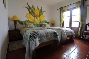 a bedroom with two beds and a flower mural on the wall at Quarto Tulipa in Vila Nova de Milfontes