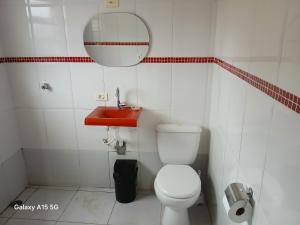 a bathroom with a white toilet and a red sink at 600 metros da praia piscina e churras 3 vagas in Mongaguá +3 photos