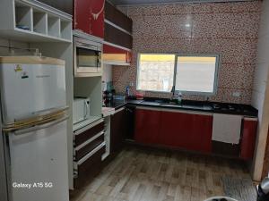 a kitchen with red cabinets and a white refrigerator at 600 metros da praia piscina e churras 3 vagas in Mongaguá